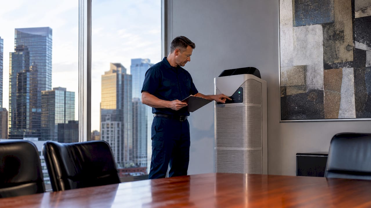 Facility manager inspecting commercial air purifier unit